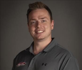 male servpro employee wearing gray polo in front of blank background